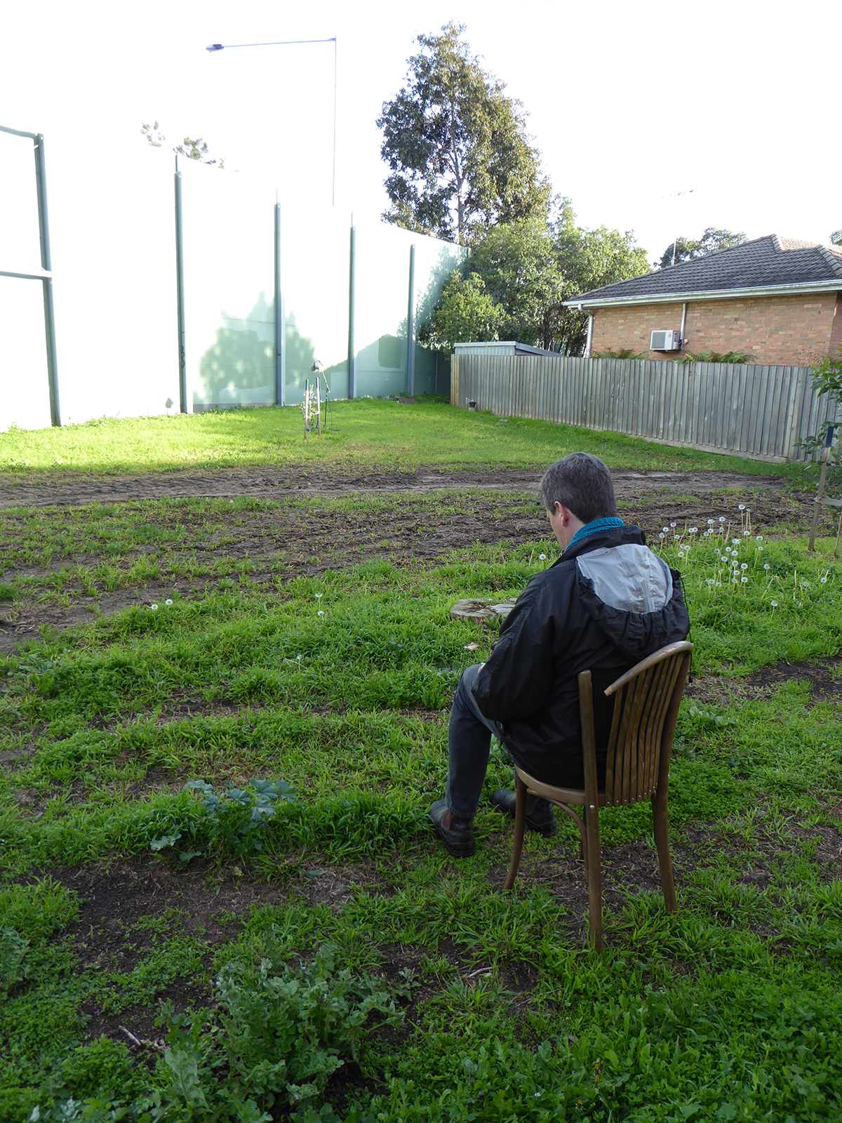 Notating traffic sound - listening to and notating sound wall traffic (conducted as part of Transurban Innovation Grant, exploring the possibilities of soundscape design systems to manage roadside traffic noise). person sat on chair outside in a garden