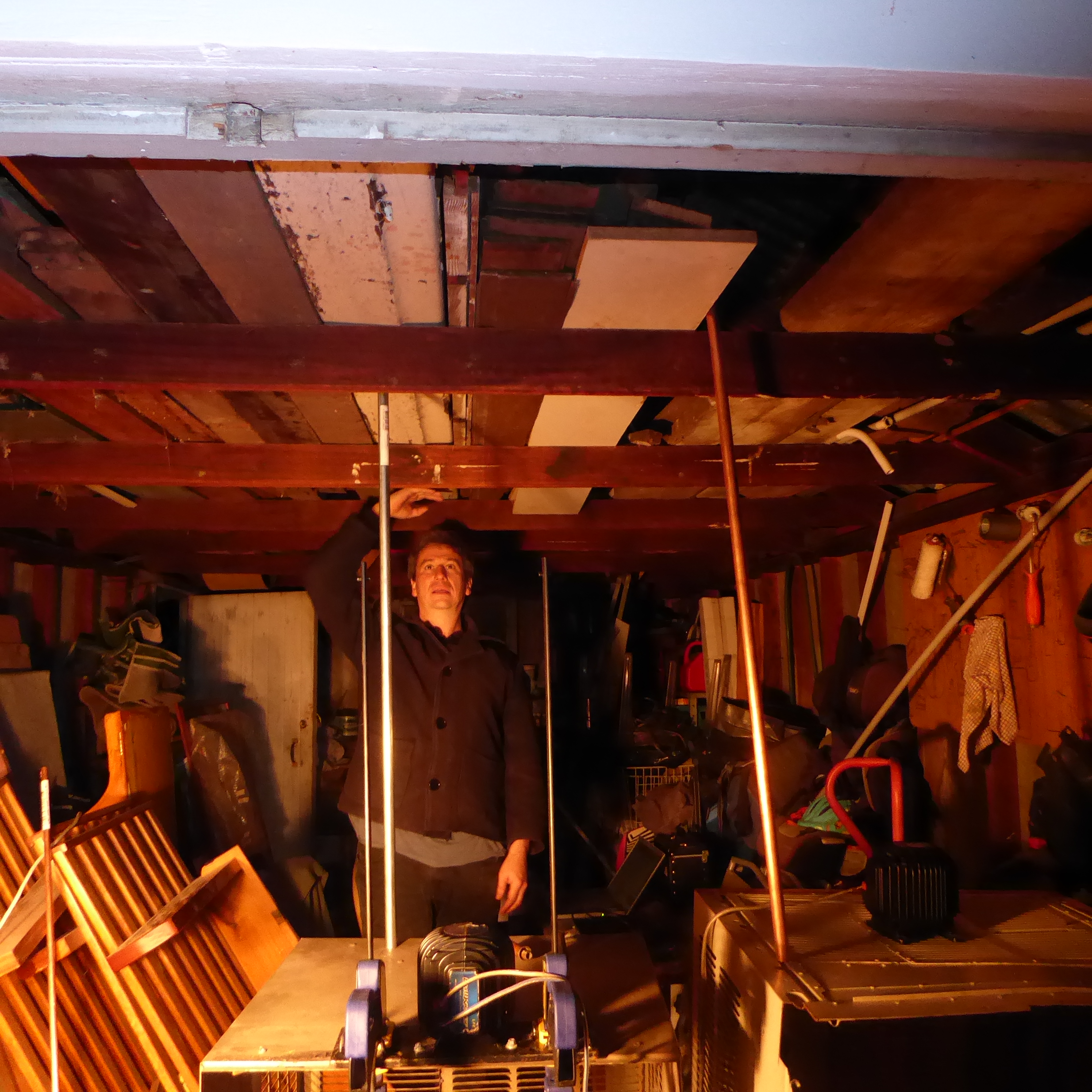 Vibrating Sheds - testing vibrational transduction in the back shed, as part of City of Casey funded research project exploring possible relationships between sound and placemaking. A man standing in a shed with speakers.